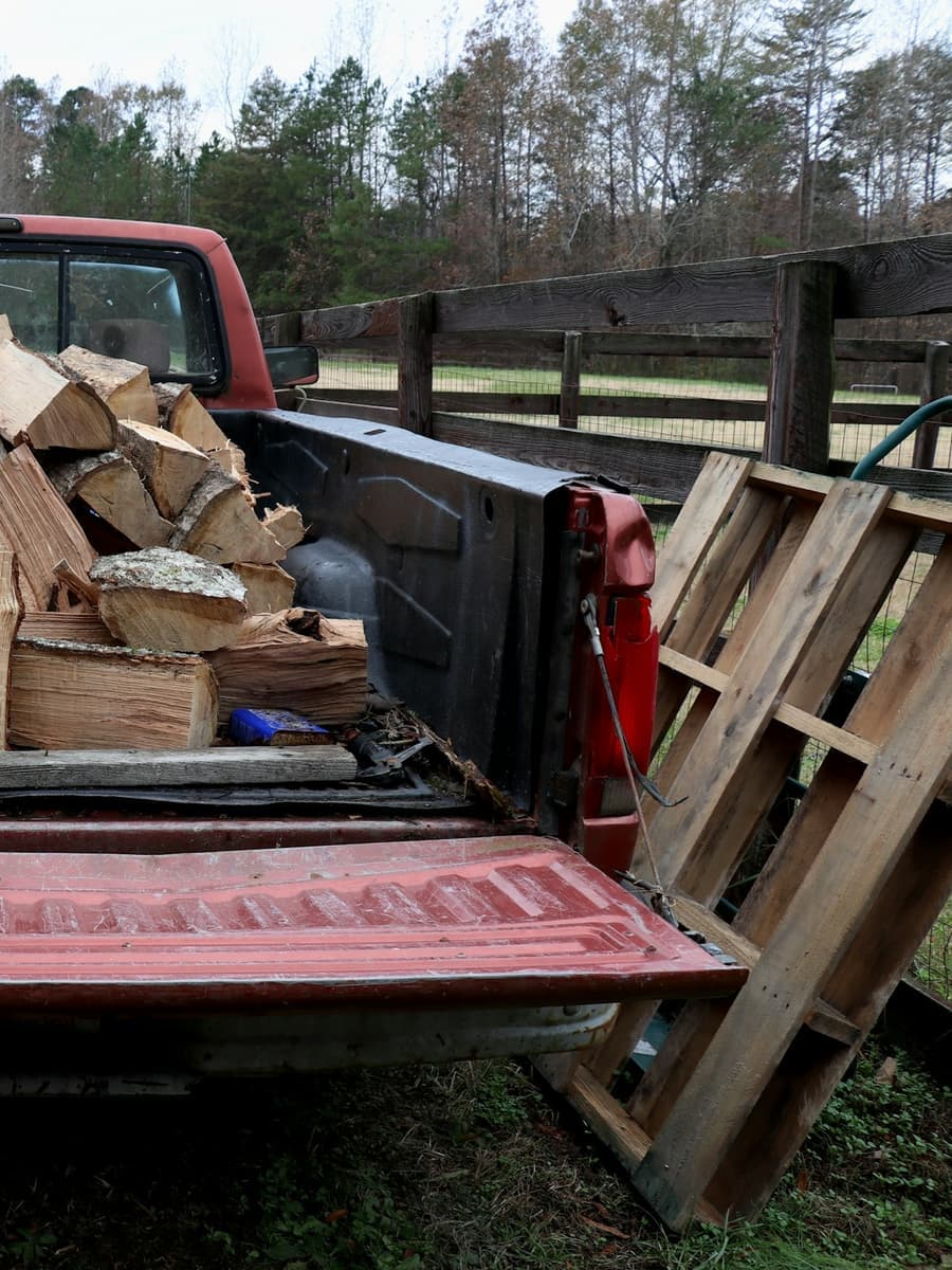 A pickup truck bed loaded with split firewood.